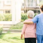 Une aide-soignante qui se promène avec une personne âgée à l'extérieur.